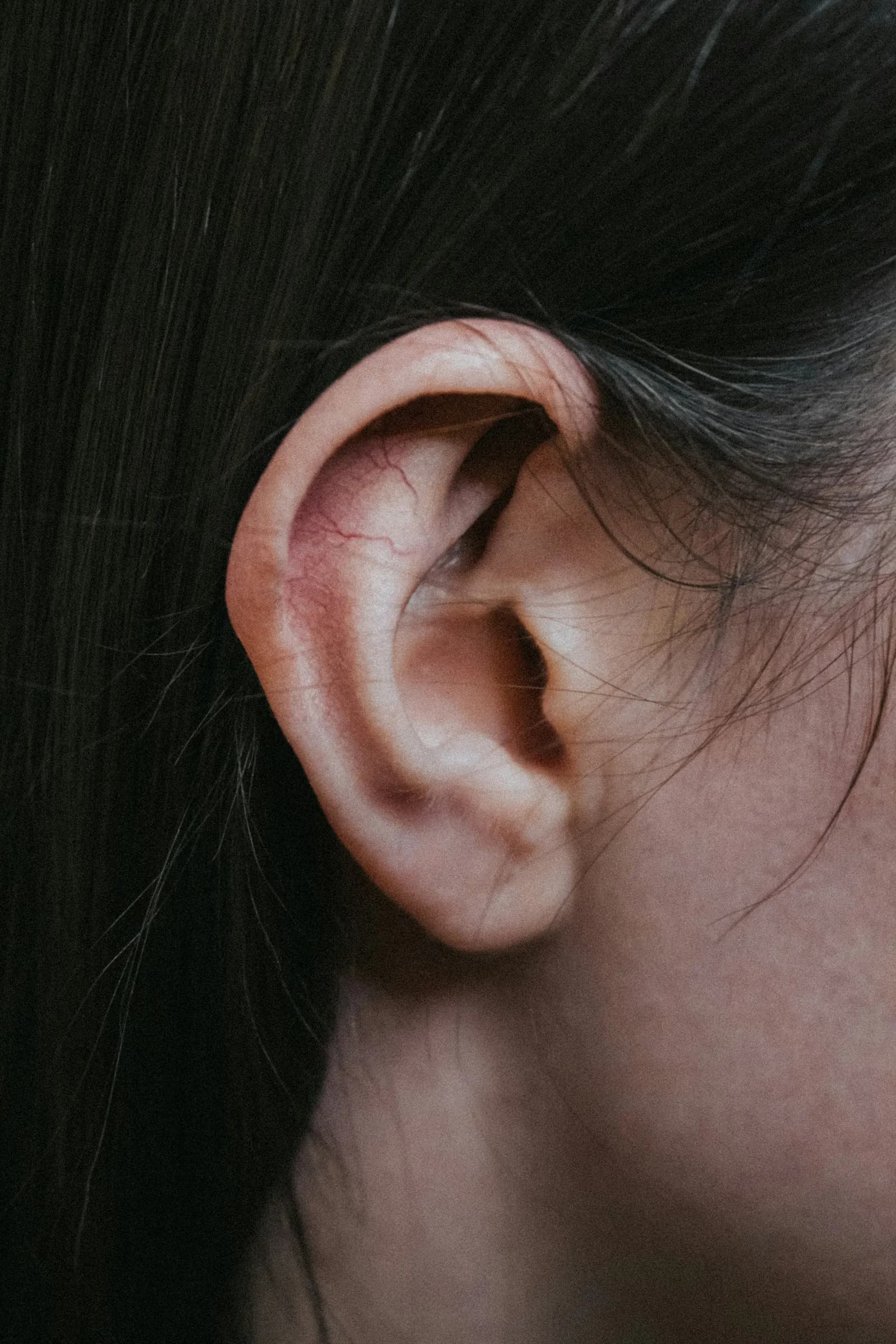 Close-up of a person's ear on a soft neutral background—illustrating the focus of tinnitus relief for ringing ears.